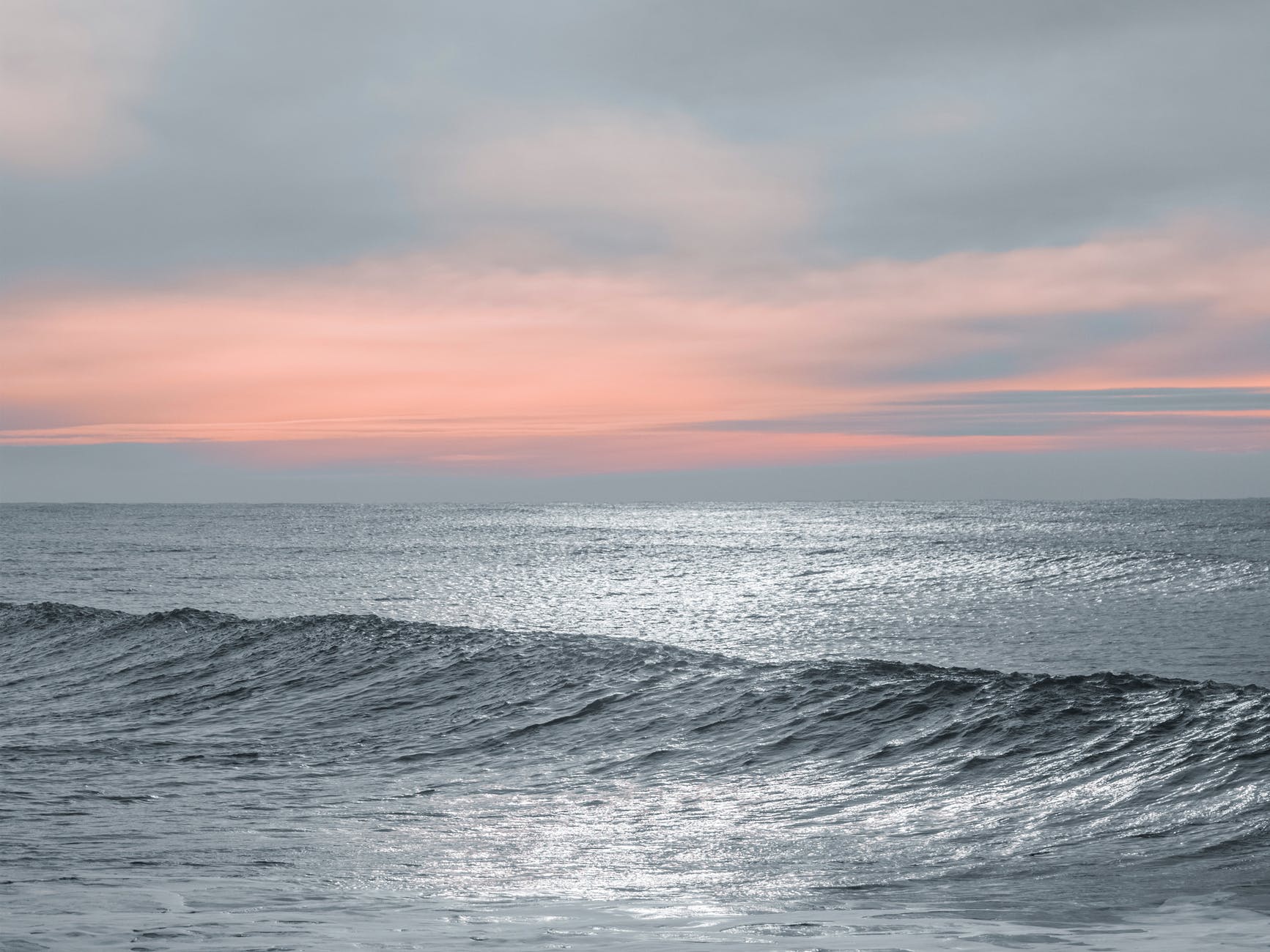 ocean waves under cloudy sky during sunset